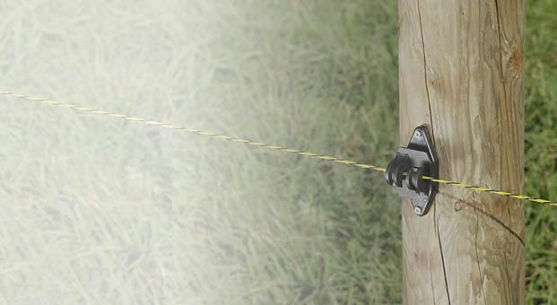 fence wire running through an insulator on a fence post